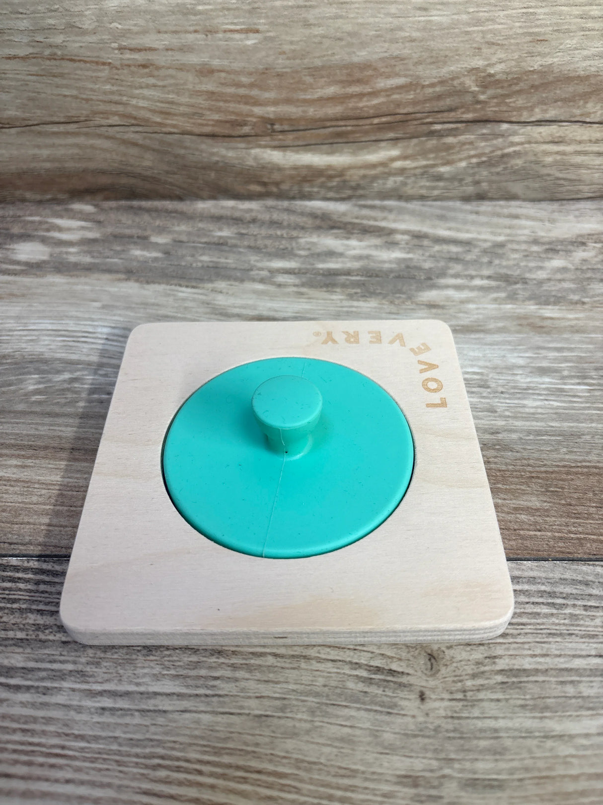 Wooden Montessori puzzle toy with green circle knob on wood background