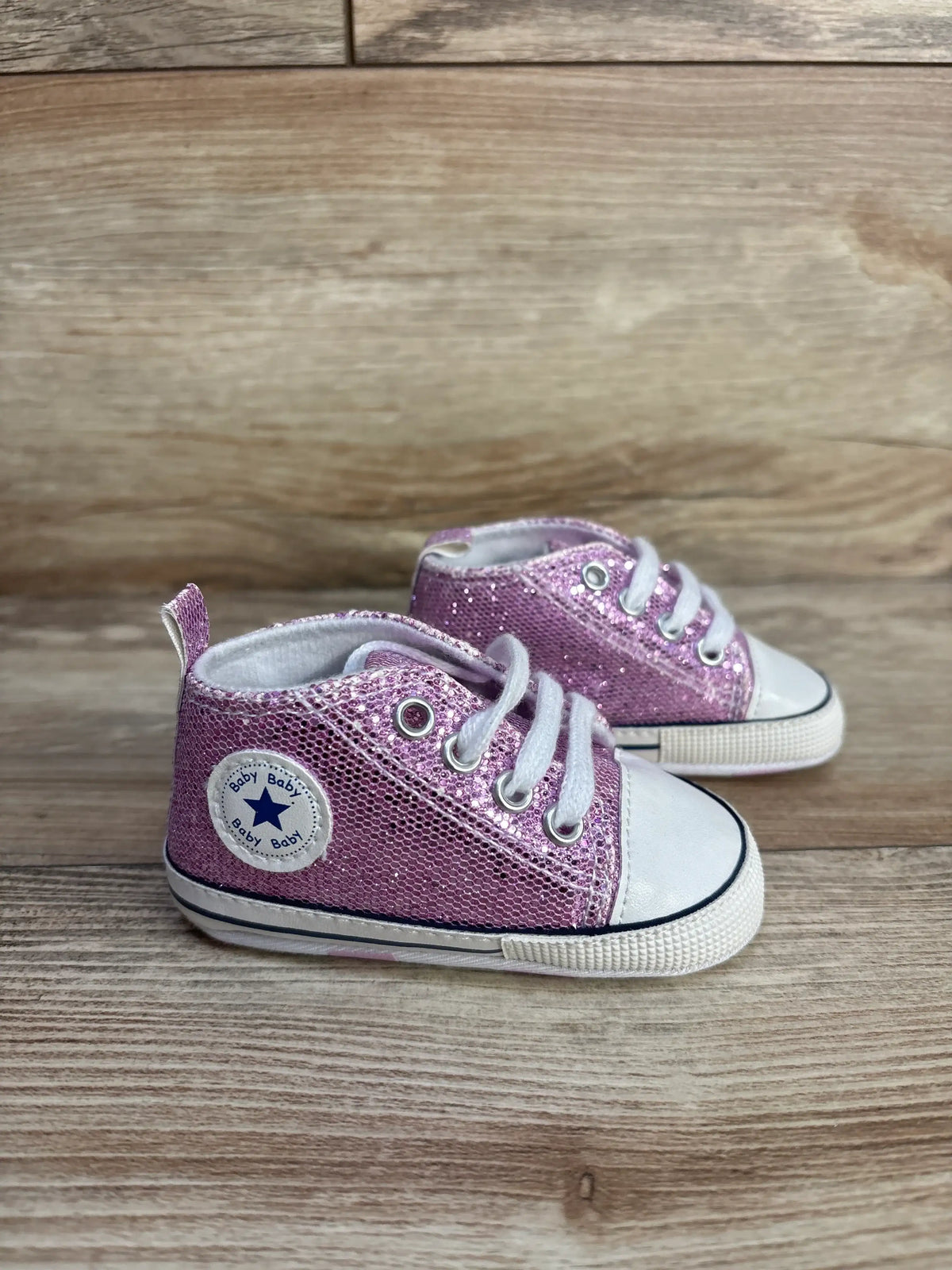 Purple glittery slip-on crib shoes by Me n Mommy To Be on a wooden surface