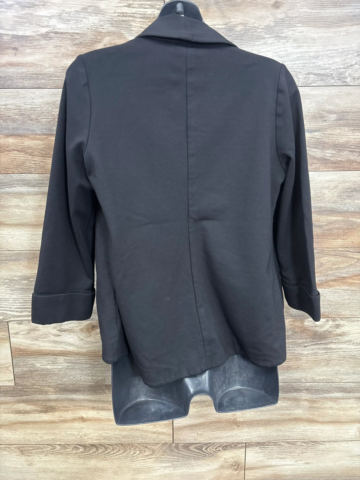Black blazer jacket on mannequin, back view, wood background, women's fashion