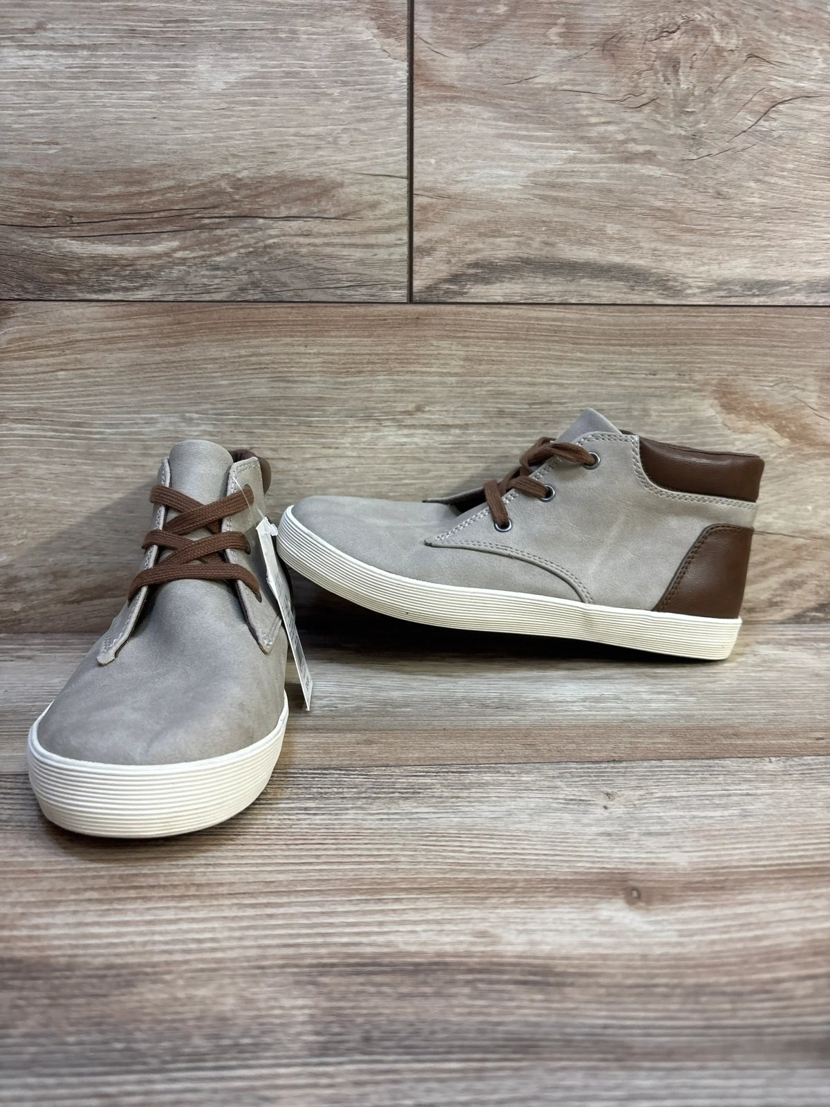 Kids grey and brown high-top sneakers with white soles on wood background