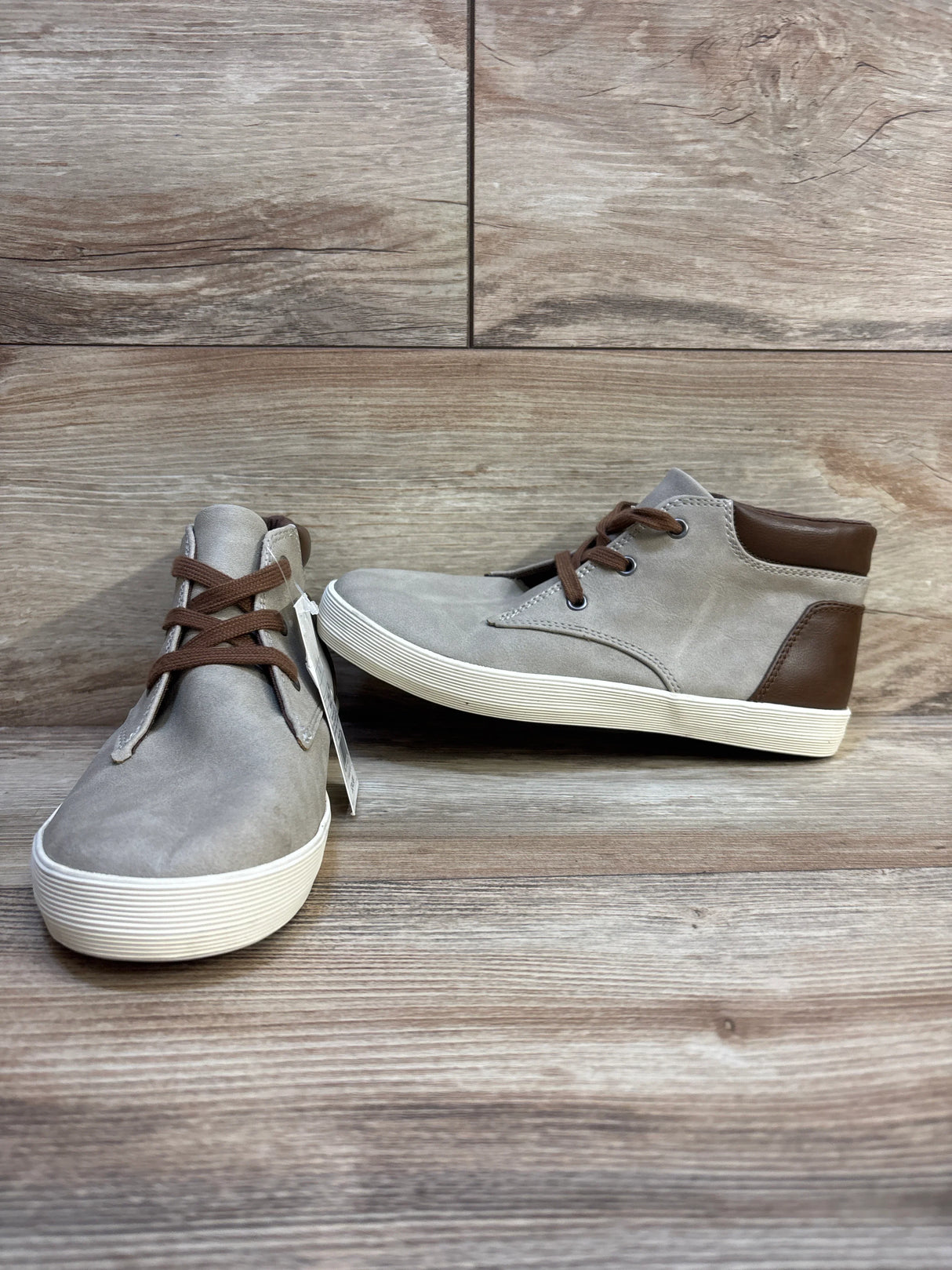 Kids grey and brown high-top sneakers with white soles on wood background