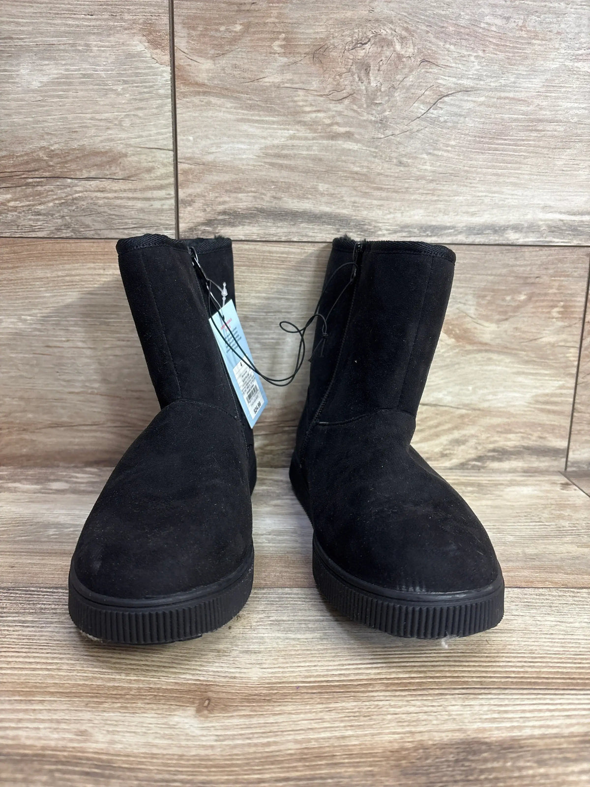 Kid's black suede boots with side zipper on wooden background, gently used condition