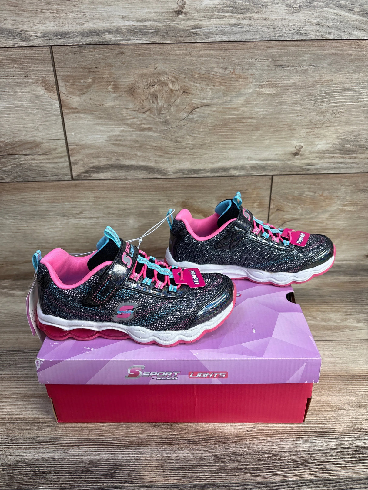 Pair of NEW Sketchers S Sport Katalyna sneakers, grey with pink accents, glitter details, and hook-and-loop straps on a purple box