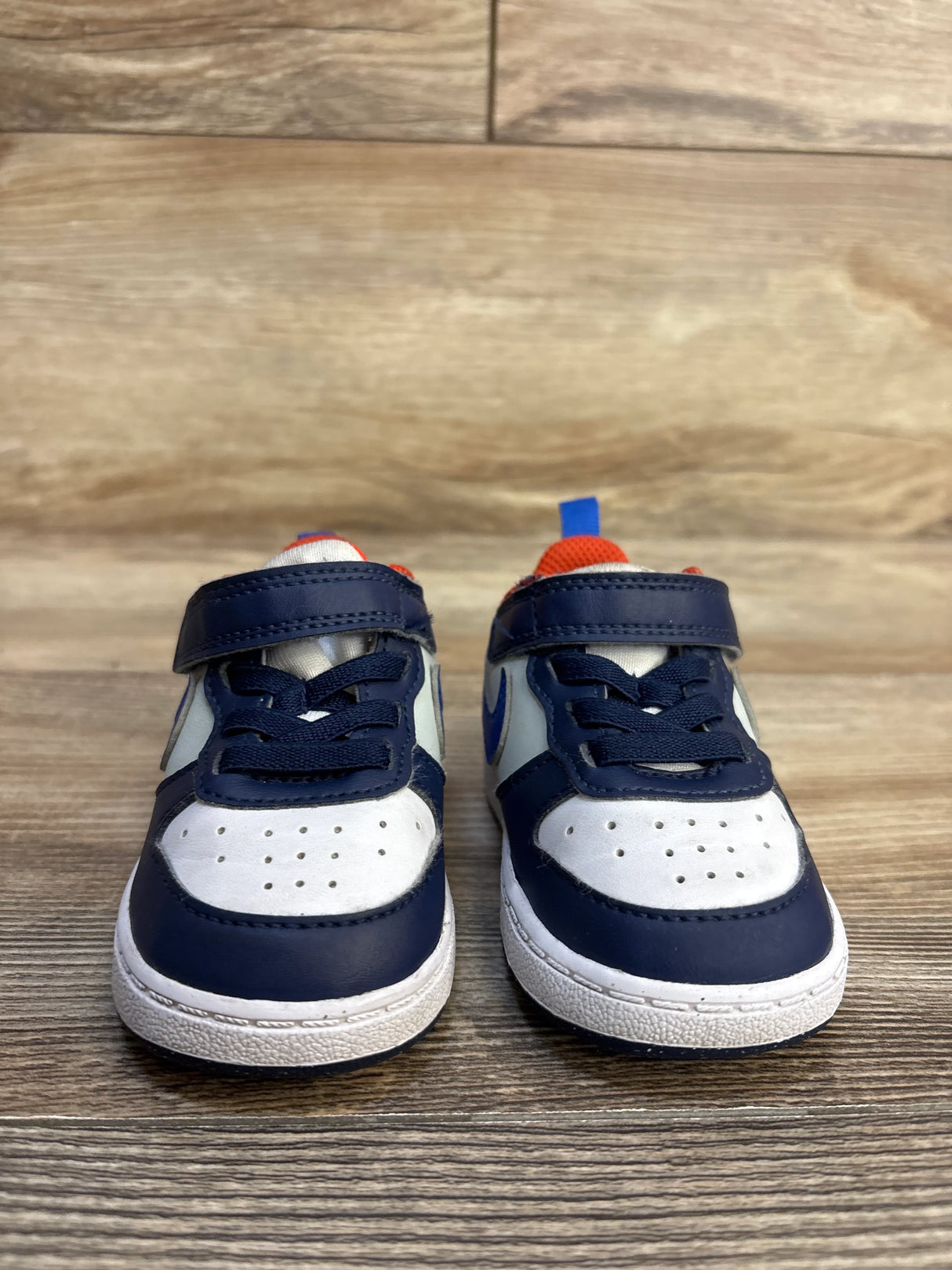Navy blue and white toddler sneakers with Velcro straps on wood floor