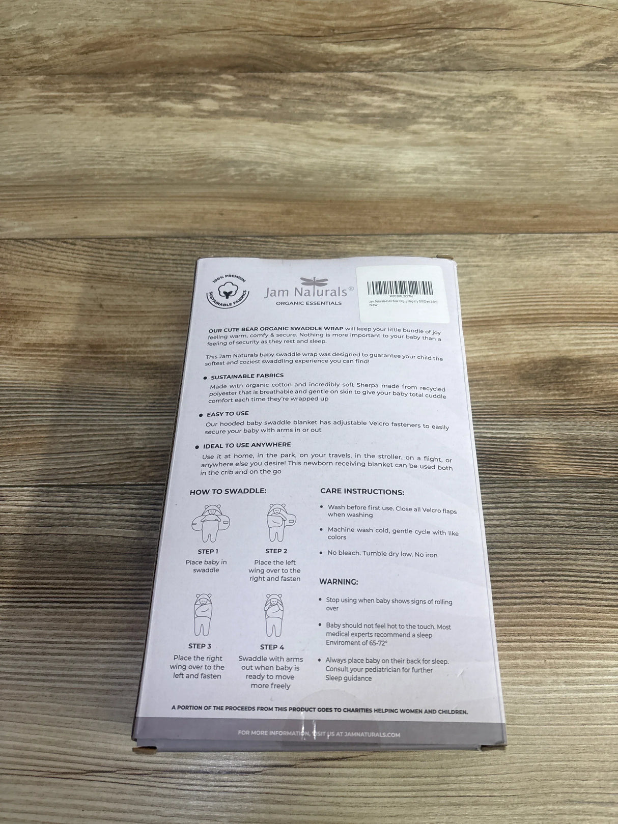 Jam Naturals Cute Bear Organic Swaddle Wrap packaging with usage steps and care instructions on wood surface