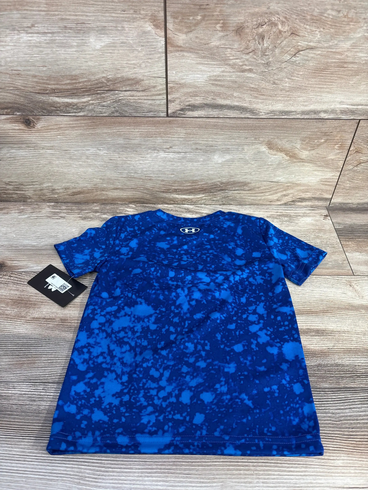 Front view of Under Armour active shirt in blue size 4T with speckled pattern and crewneck on a wood floor