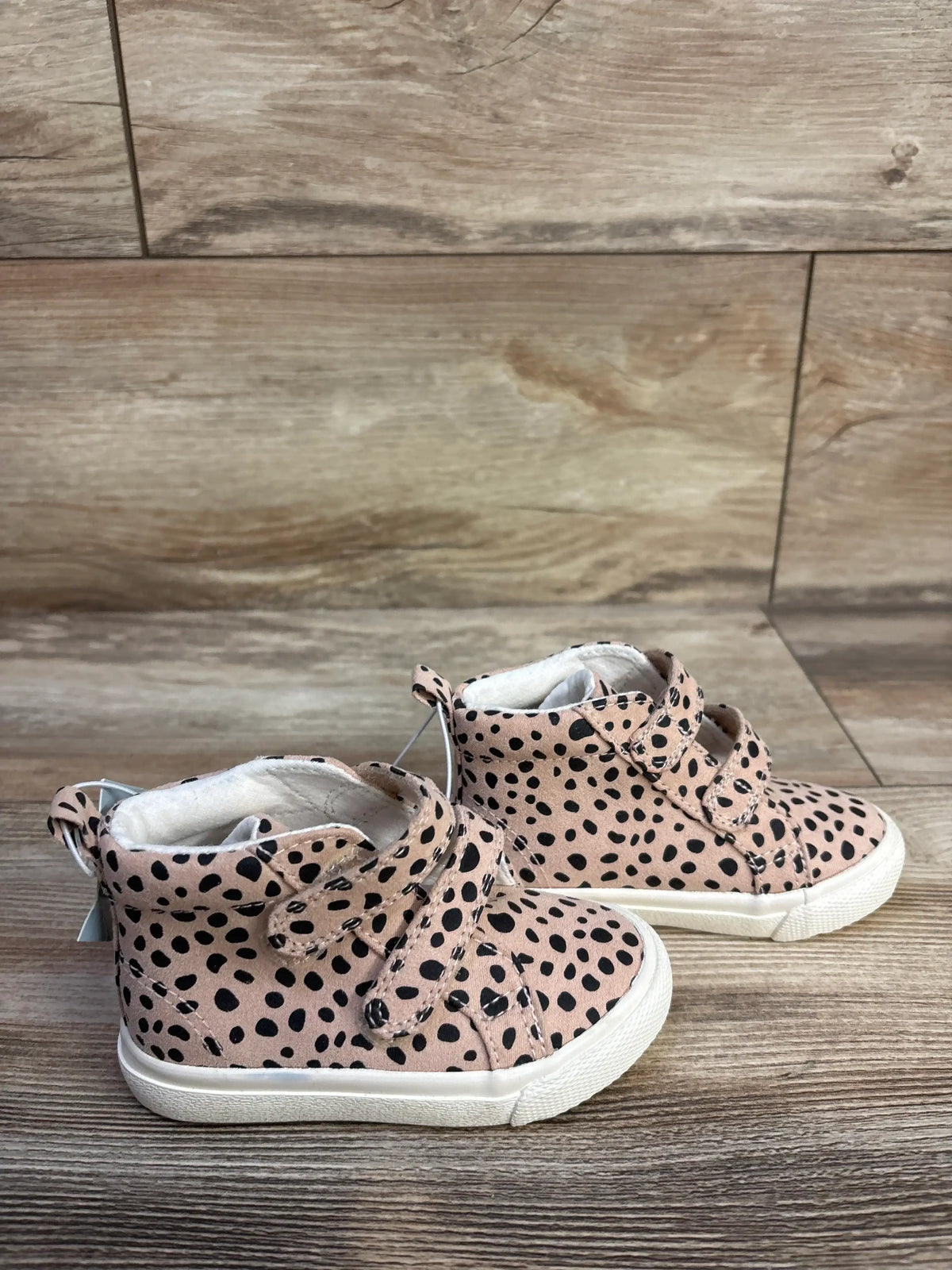 Side view of Cat and Jack Lucky Leopard toddler high-top sneakers showcasing beige fabric with black leopard spots, double Velcro straps and white rubber soles on wood floor