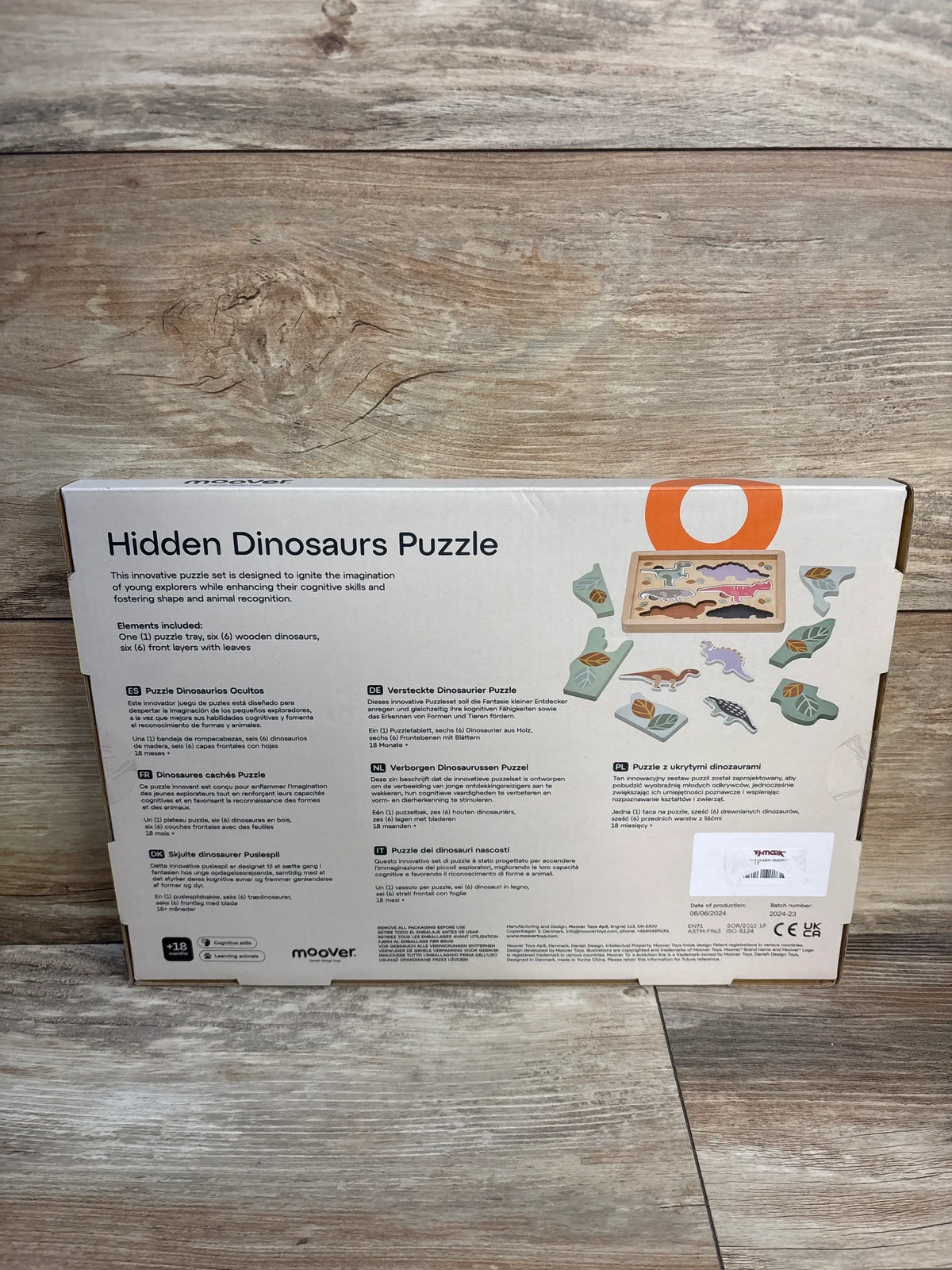 Back view of Moover Hidden Dinosaur Puzzle box showcasing layered dinosaur pieces with a wood grain background