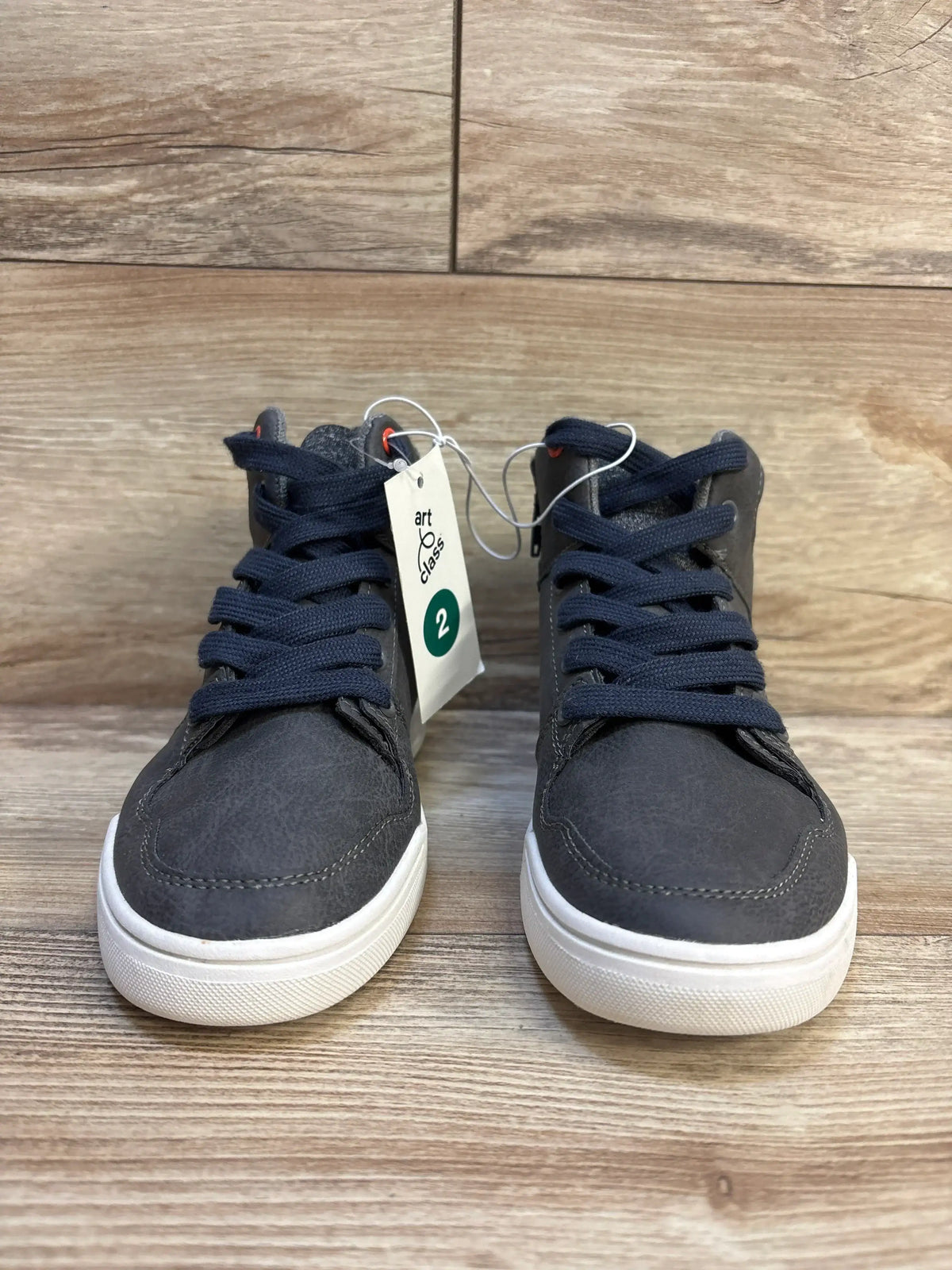 Front view of Art Class Geoff kids high-top sneakers in grey with navy laces, white rubber soles and visible size 2 hang tag on wood floor