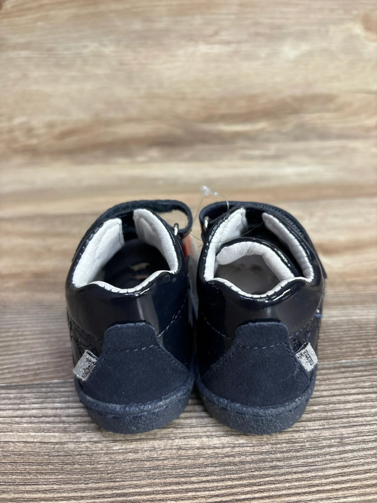 Back view of Melania navy double velcro rhinestone baby sneakers showcasing cushioned white interior on wooden surface