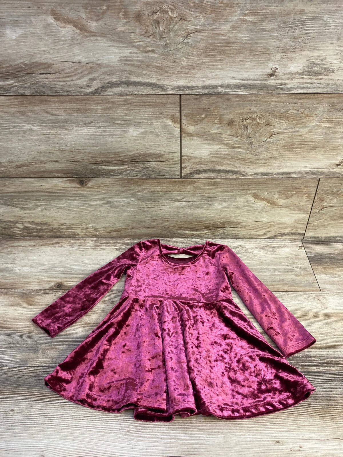 Children's Place burgundy crushed velvet long sleeve dress for toddlers on wood background