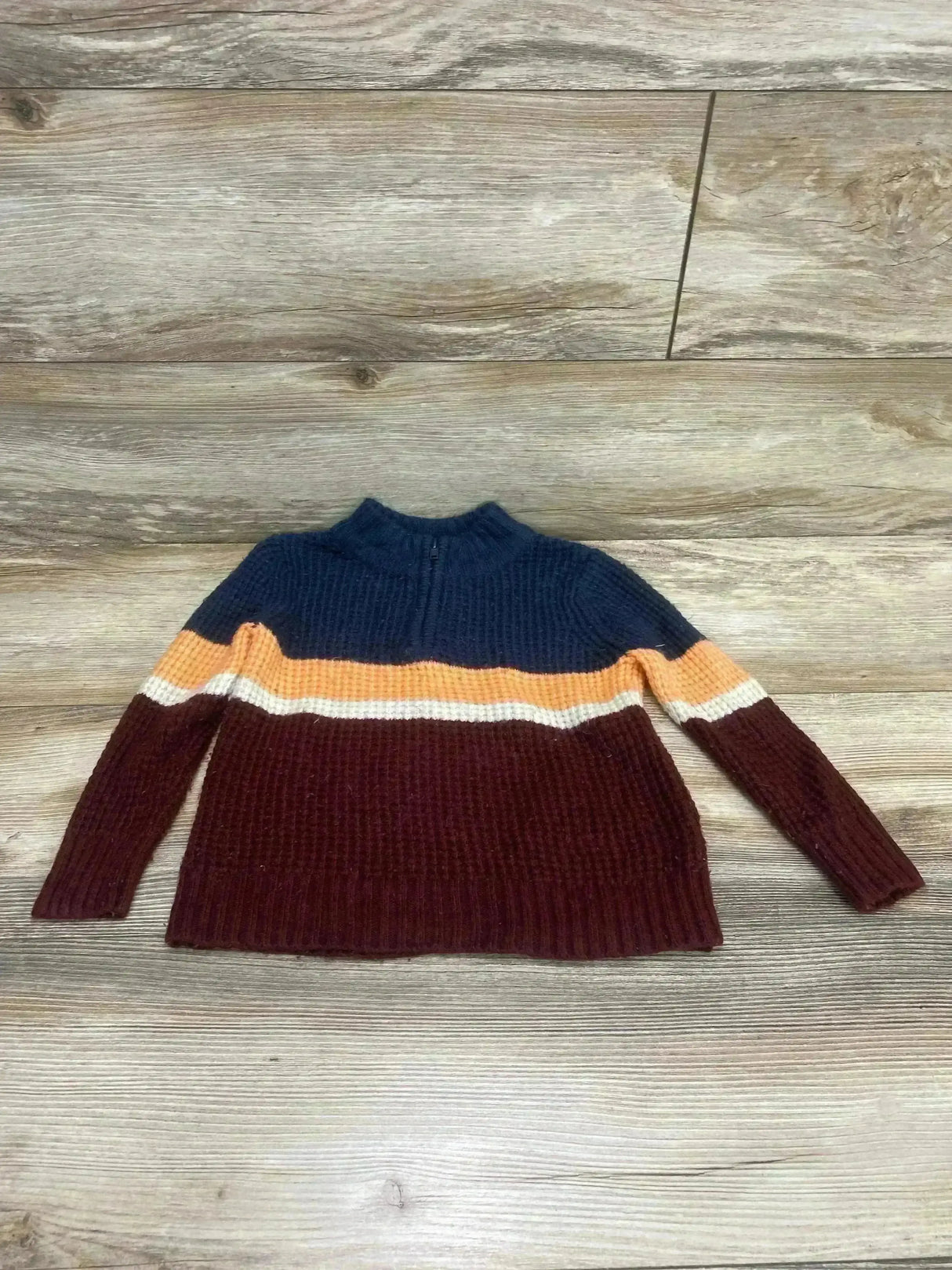 Front flat-lay of Cat and Jack quarter-zip colorblock sweater with navy, orange, white and maroon bands on wood background