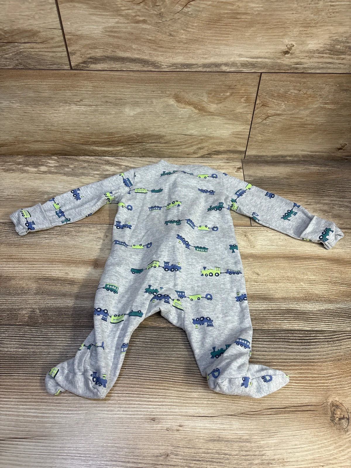 Full view of Carter’s grey sleeper with long sleeves, covered feet, and train print on a wood floor