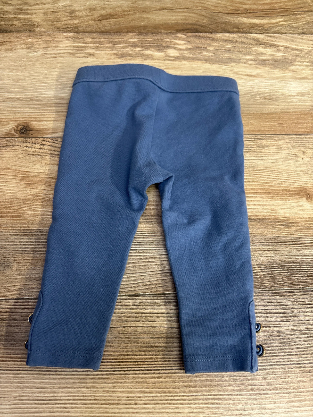 Blue toddler leggings with button details on wooden surface, children's clothing