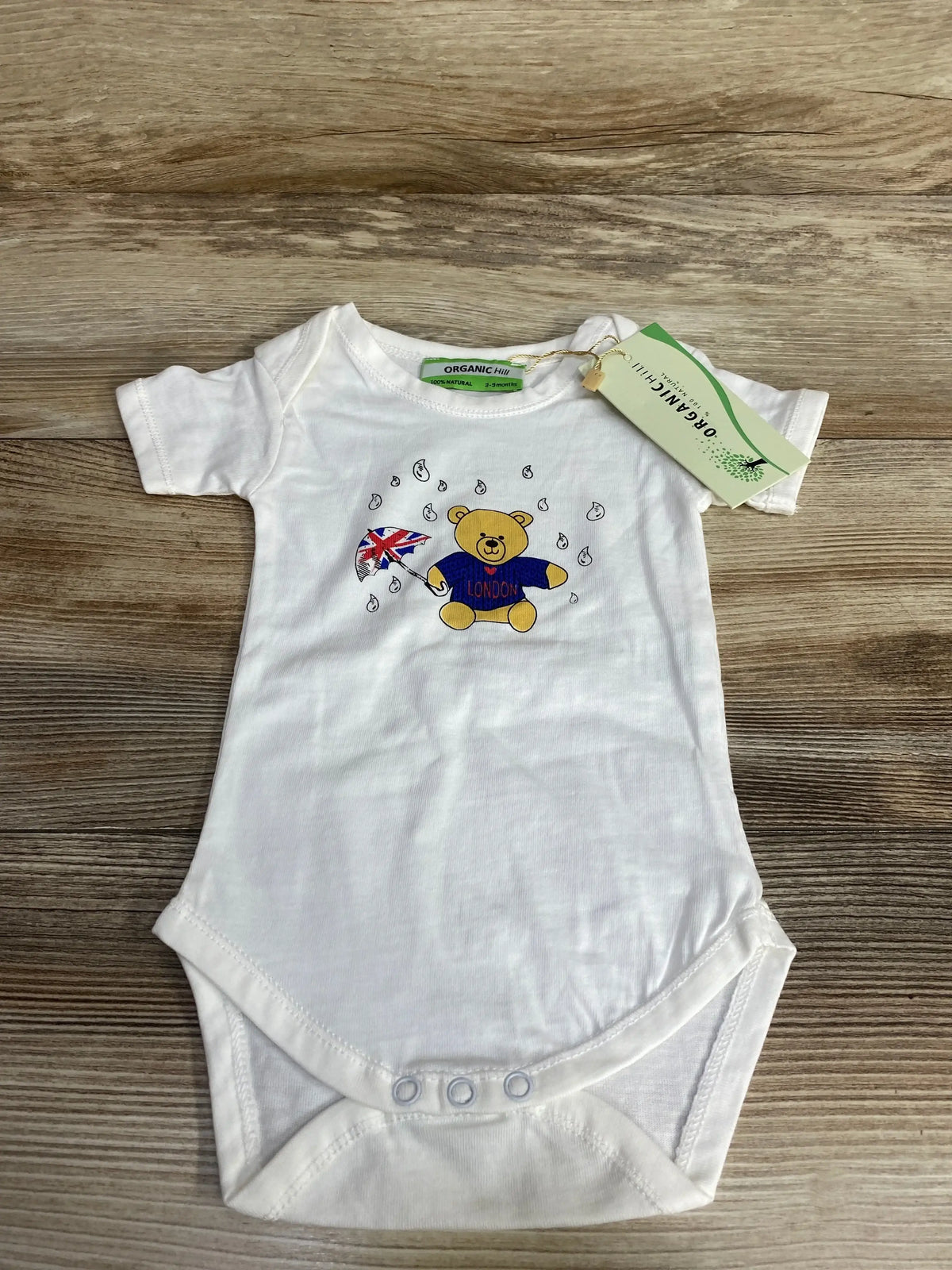 White organic cotton baby onesie with teddy bear holding Union Jack umbrella and London sweater design