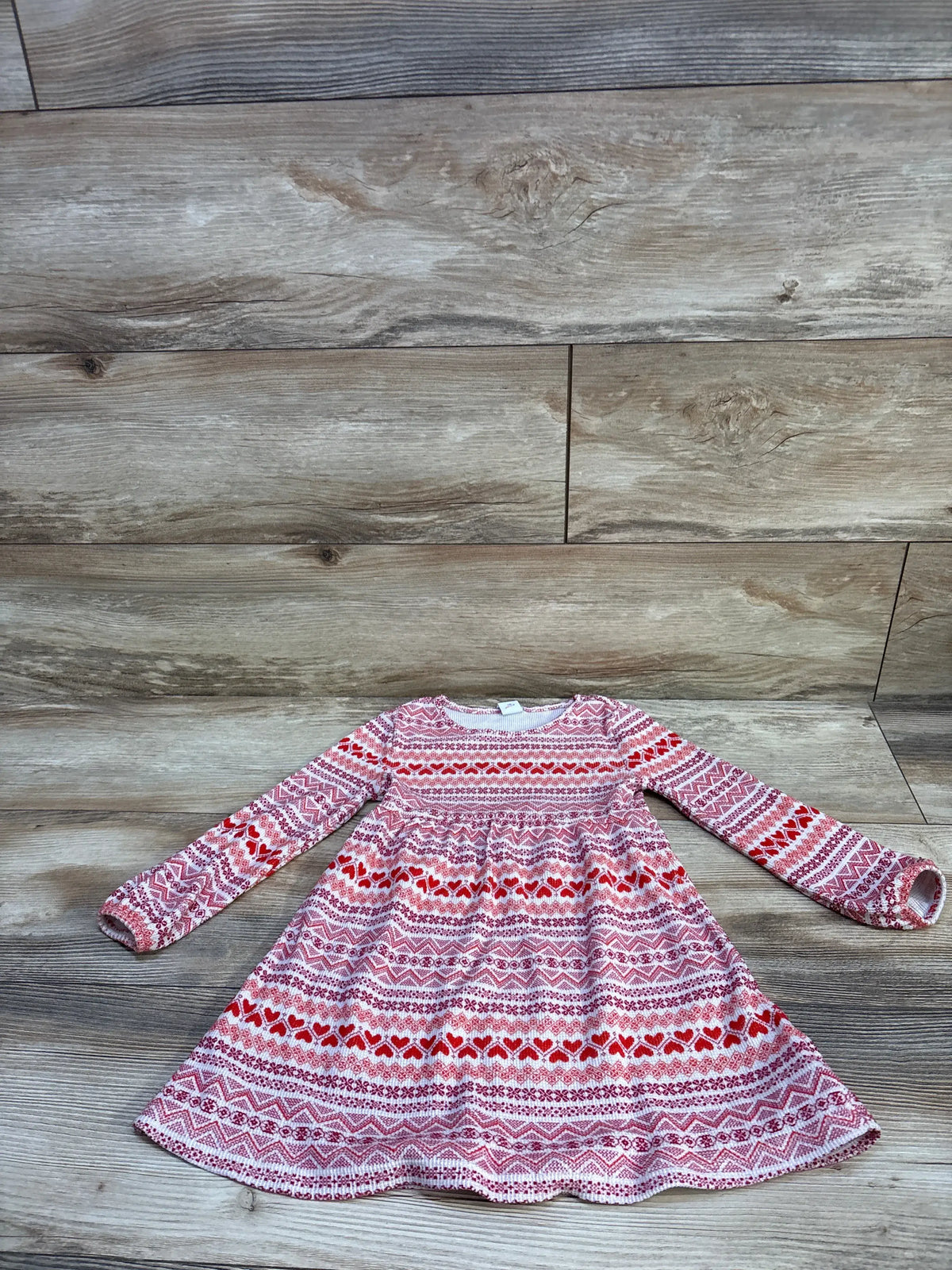 Front view of Old Navy thermal knit dress, pink size 4T, with long sleeves and red and white patterned knit on wood flooring