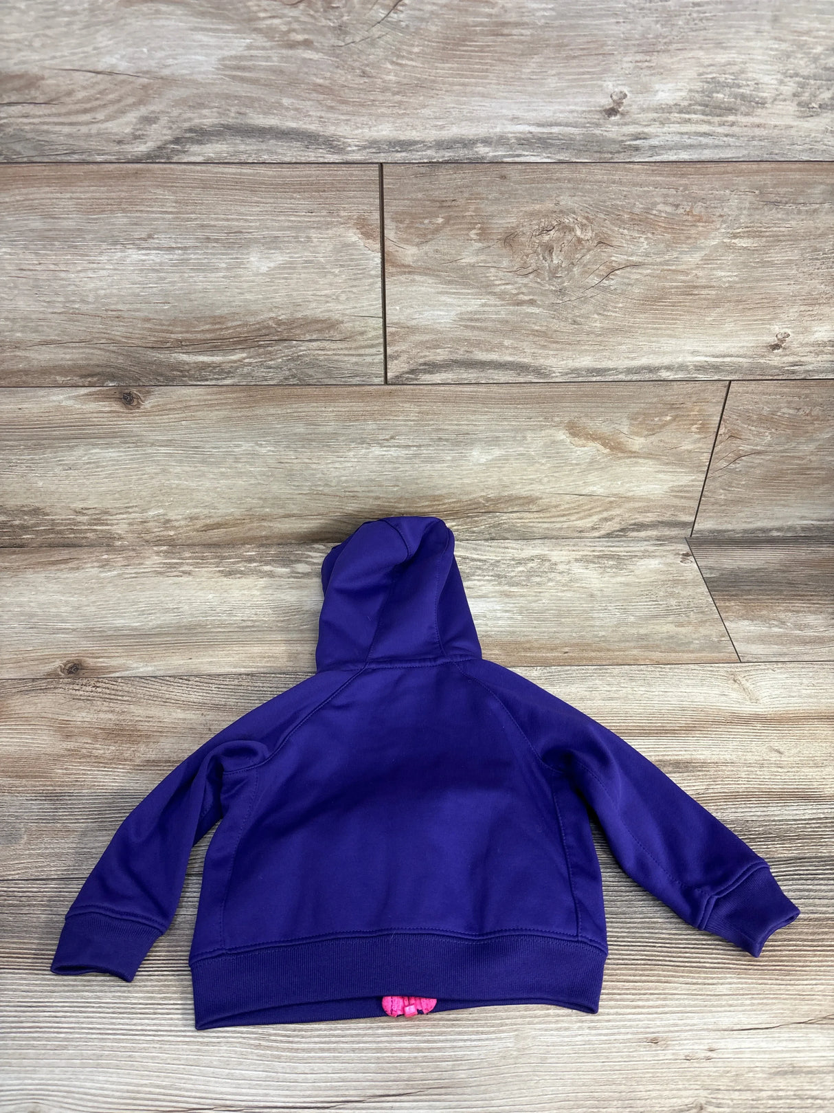 Purple kids hoodie laid flat on wood floor, viewed from the back