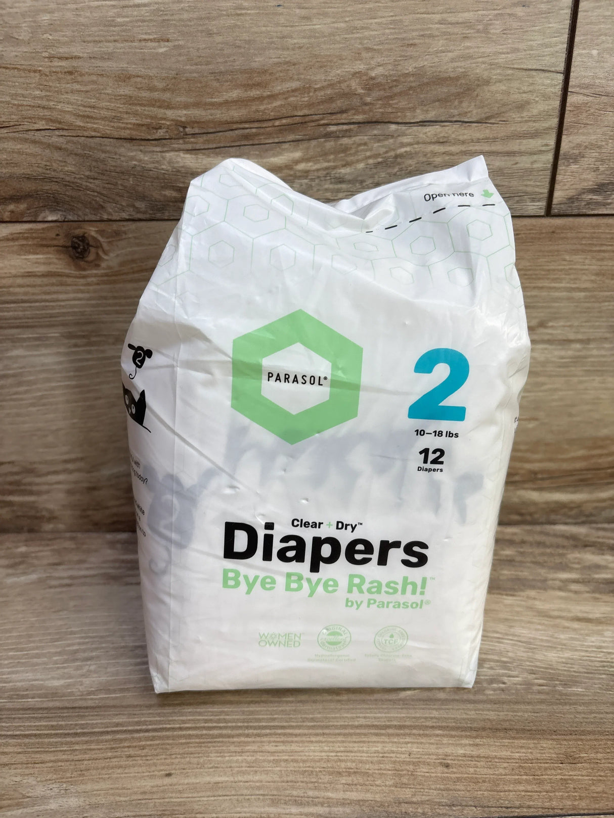 Front view of Parasol diaper pack showcasing size 2 (10-18 lb), logo and Clear + Dry Bye Bye Rash text on wood background