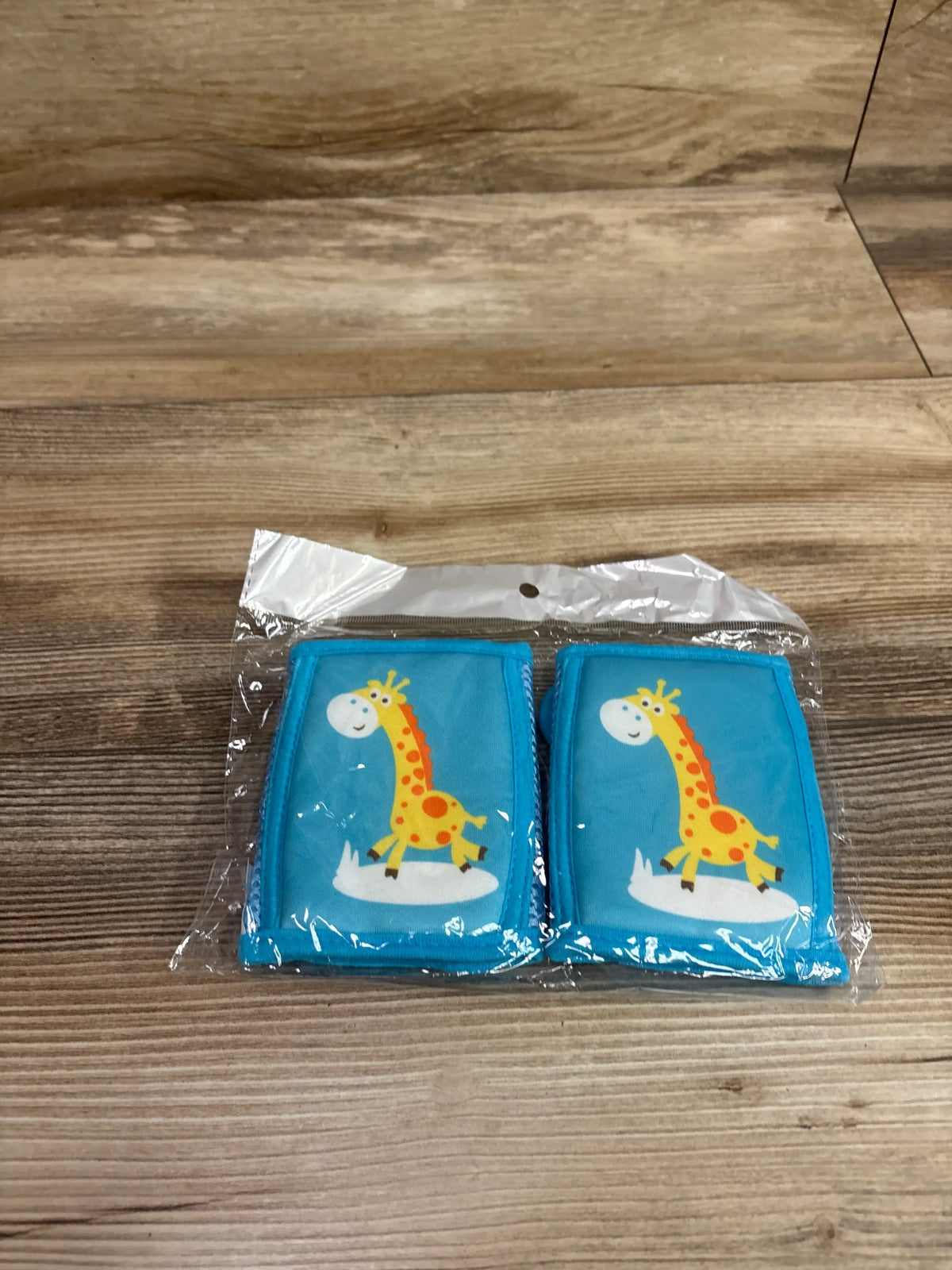 Two blue Lipfer baby crawling knee pads featuring a cute yellow giraffe, packaged in clear plastic.