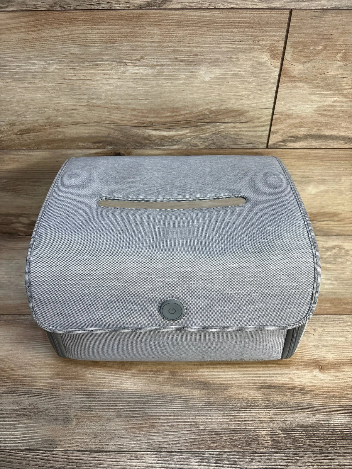 Top-front view of Munchkin 59S UV cleaning bag showing front power button and top slit on gray fabric on wooden floor