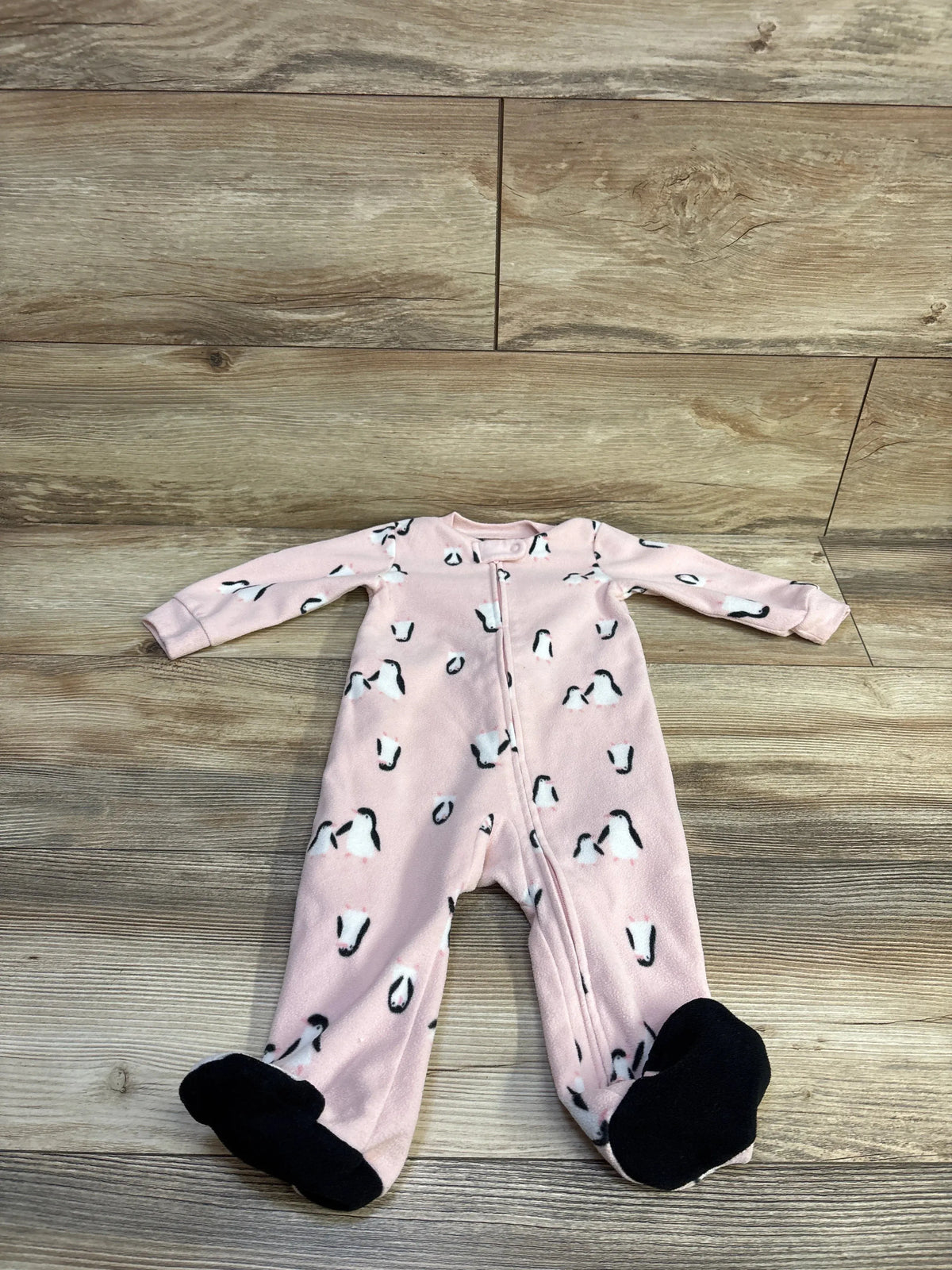 Front view of Carter’s pink blanket sleeper, size 9m, showcasing penguin print, front zipper and snap collar on wood floor