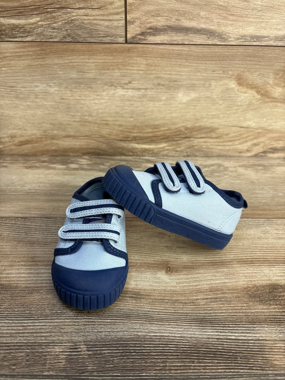 Two strap blue and grey baby sneakers on a wooden surface
