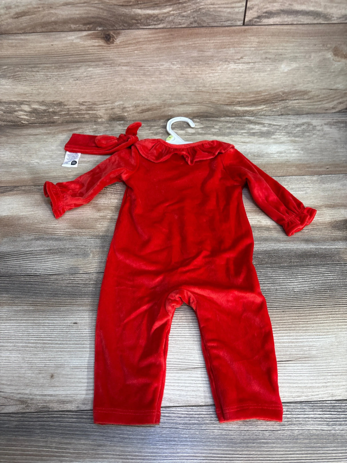 Red velvet baby romper with matching headband on wood background