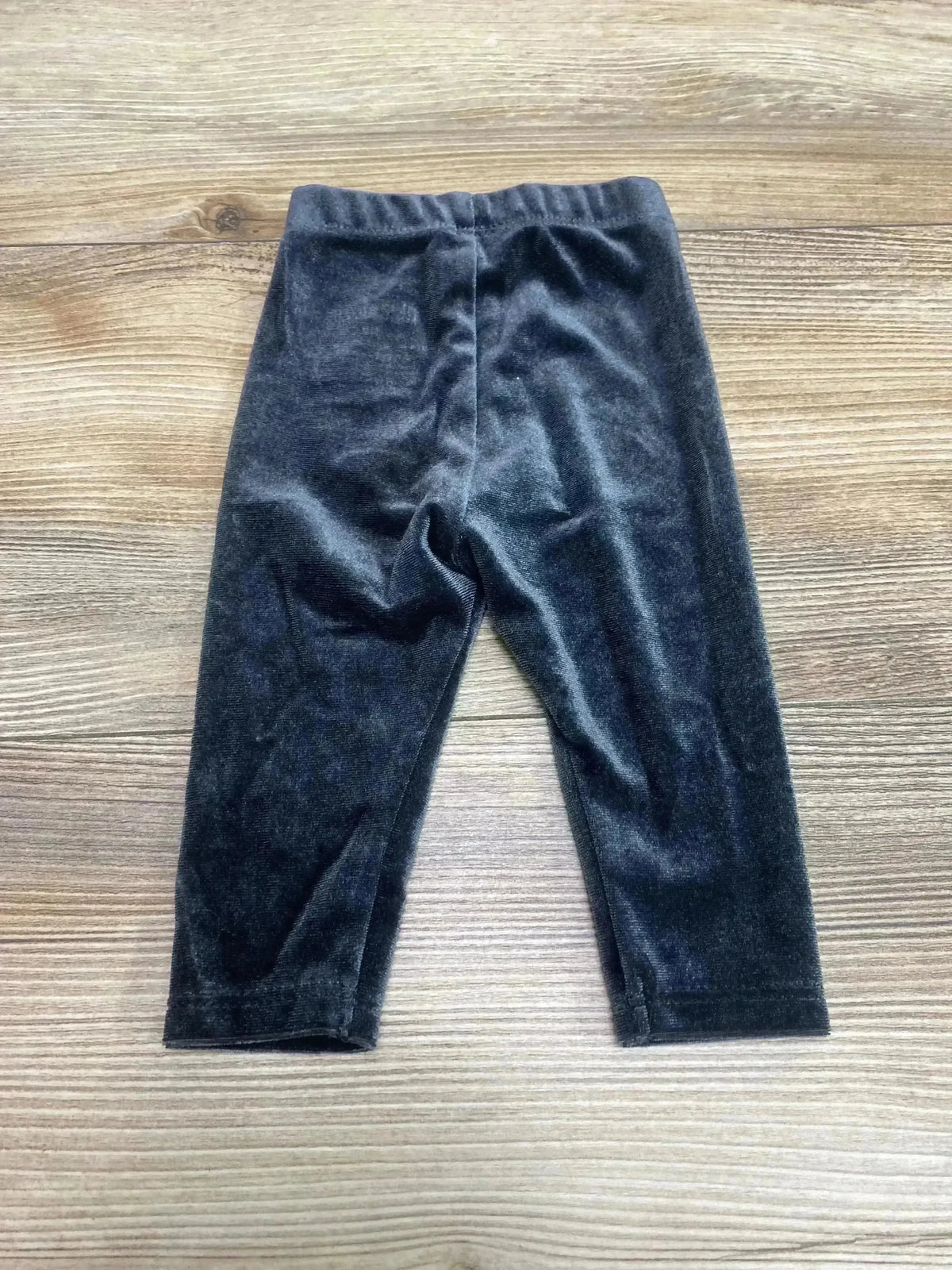 Front view of newborn Okie Dokie velour leggings in black showing elastic waistband and soft plush fabric on wood background