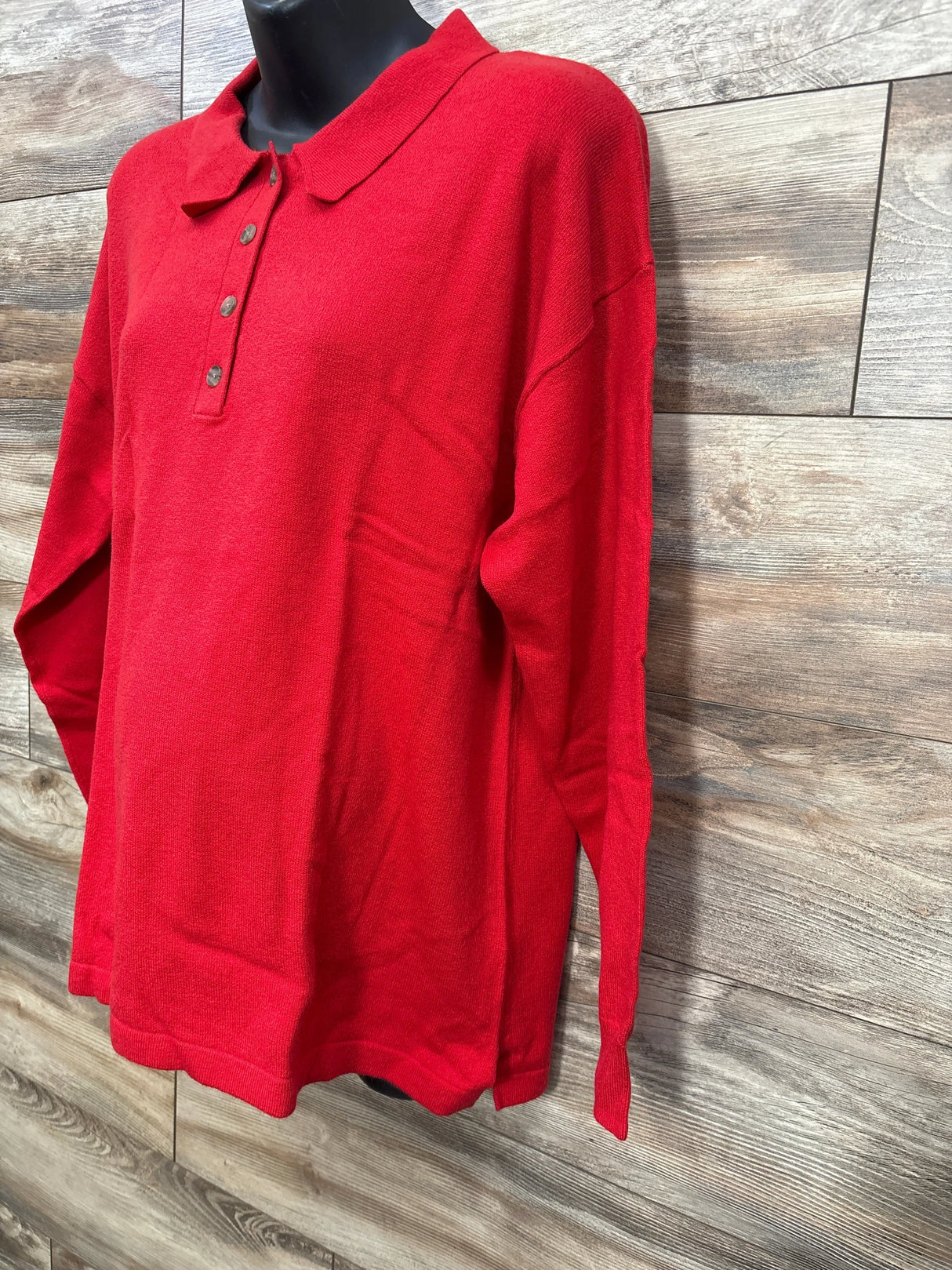 Red long-sleeve polo sweater with three buttons on black mannequin against wooden background