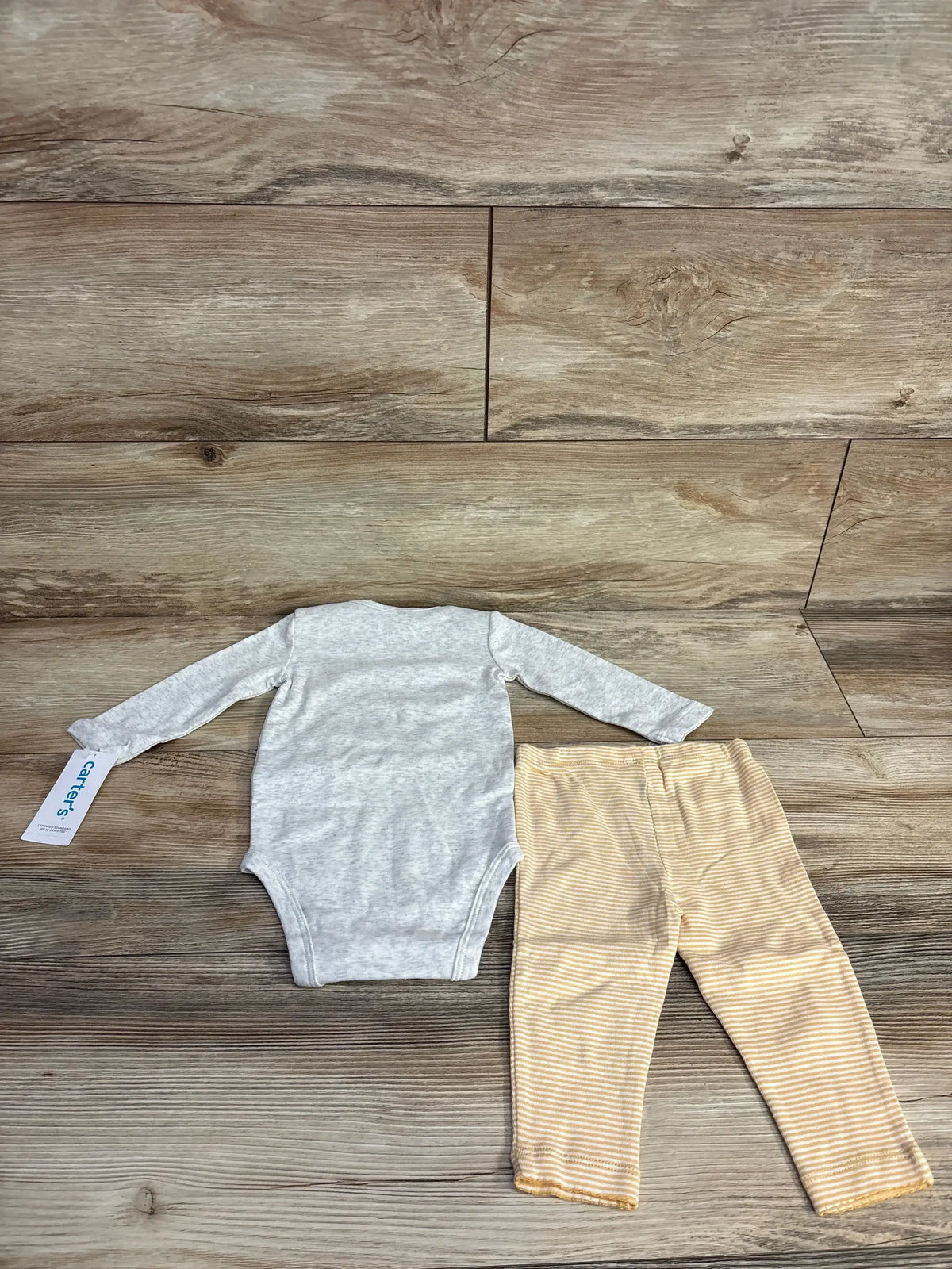 Gray baby long sleeve bodysuit with beige striped leggings on wood background