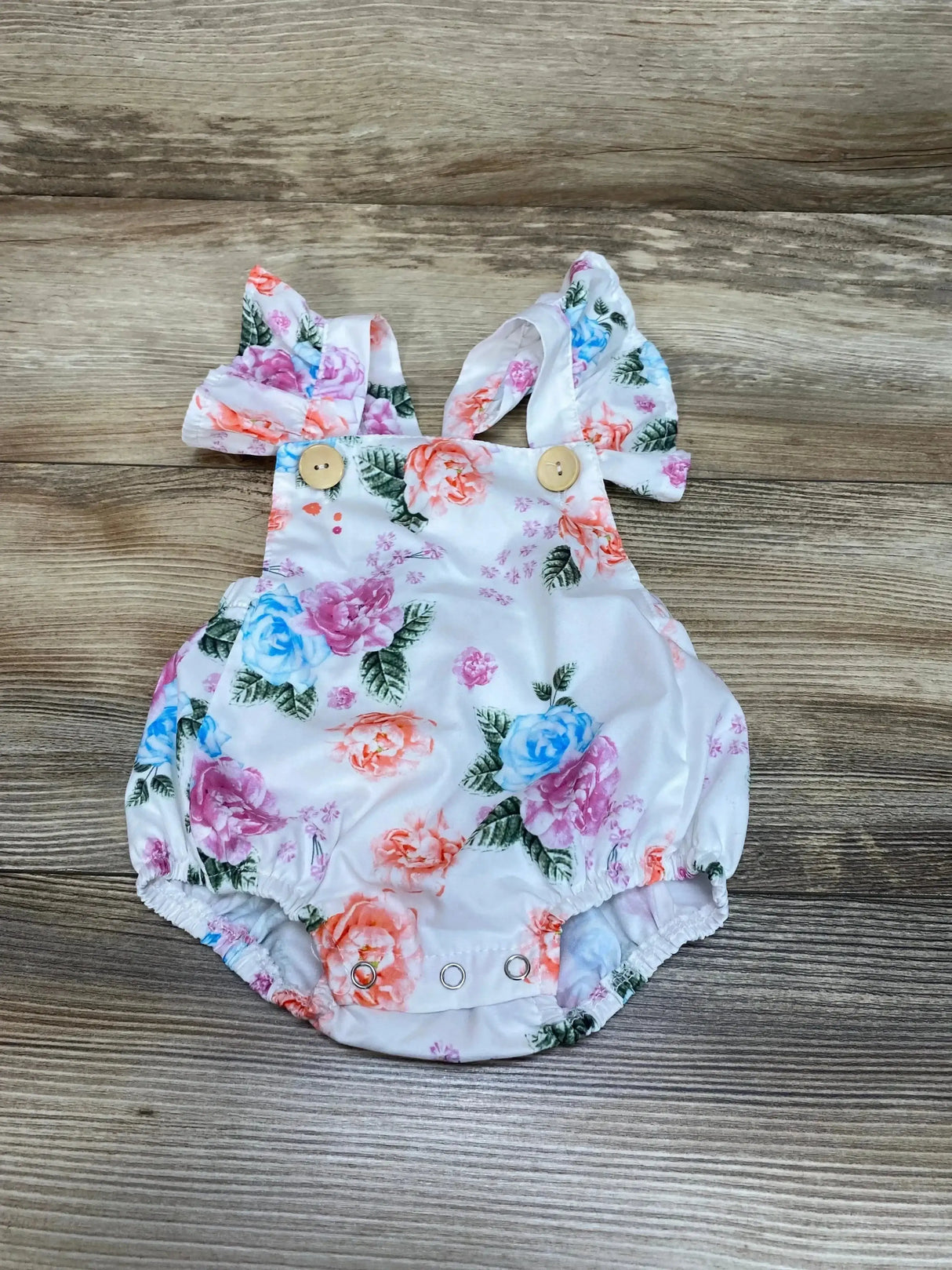 Front view of white floral baby bubble romper 3-6M with ruffled sleeves and elasticized leg openings on white background