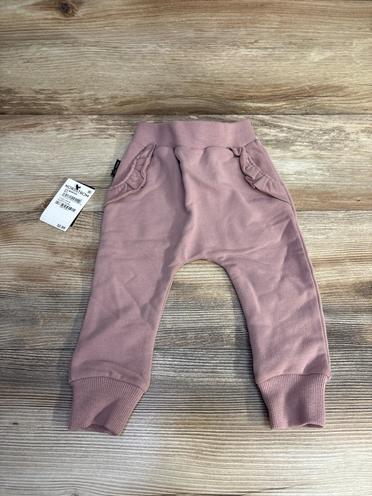 Pink toddler sweatpants with ruffle pockets and ribbed cuffs on wooden surface with Nordstrom price tag