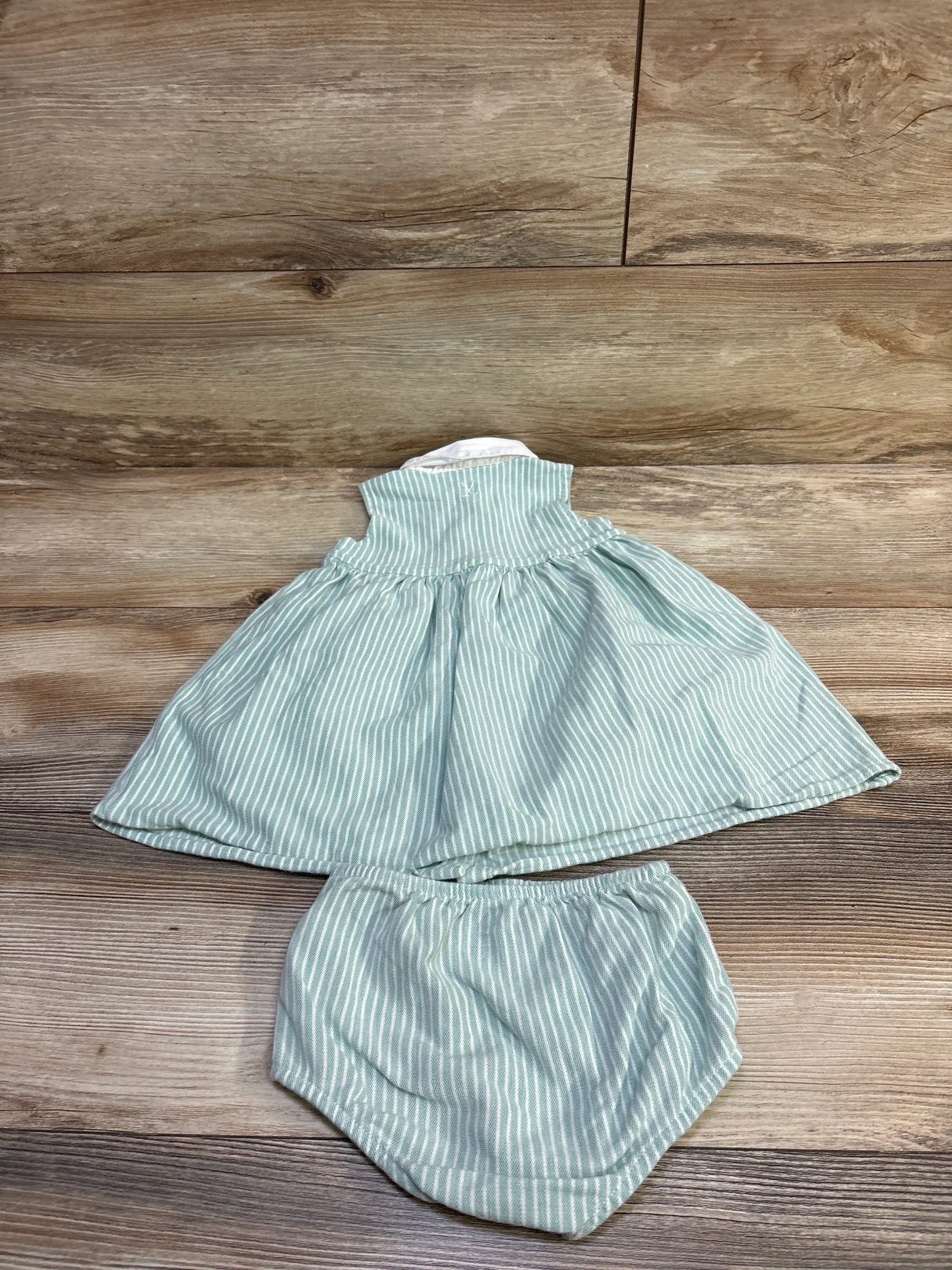 Flat lay of Ralph Lauren mint striped cotton dress with matching bloomers, ribbed collar and full skirt on wood background