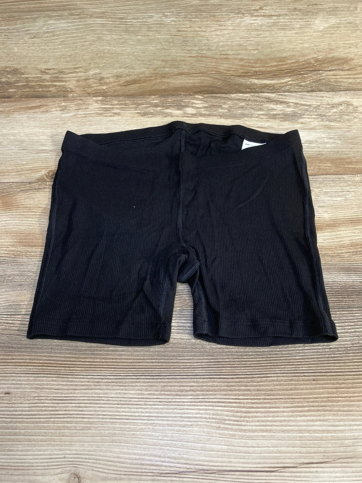 Flat-lay of black Gap maternity ribbed pajama shorts, size XS, showing elastic ribbed waistband and short inseam on wood floor