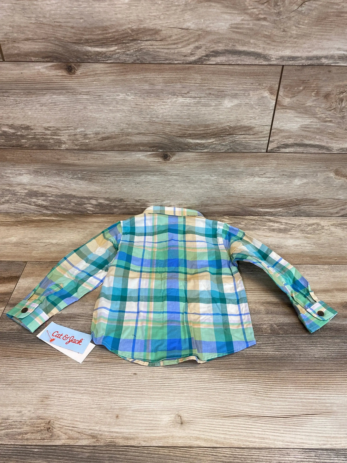 Back view of toddler Cat and Jack long-sleeve plaid button-up shirt in green, blue, and cream showing collar and button cuffs on wood background