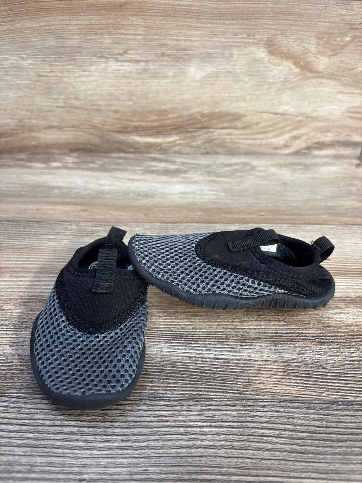 Pair of grey Wonder Nation aqua sock water shoes for kids on a wooden background.