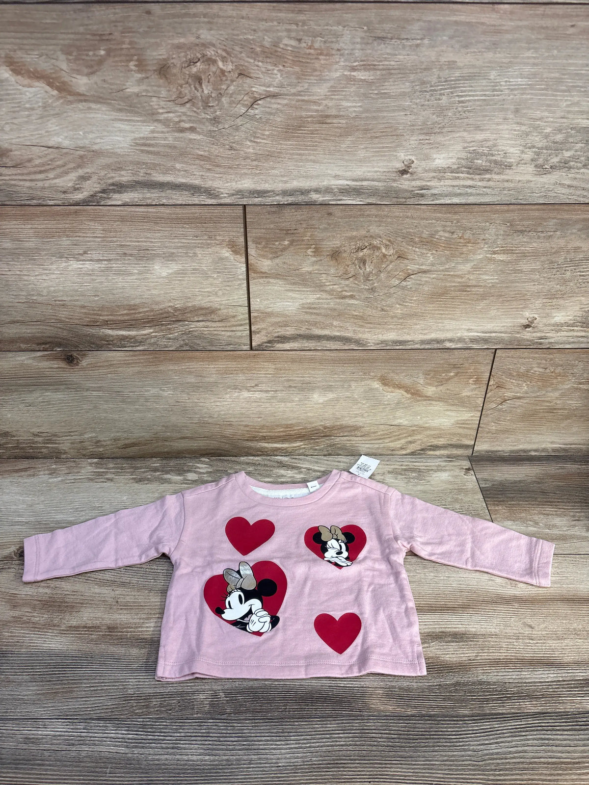 Front view of pink Baby Gap Disney Minnie Mouse long sleeve shirt, size 6-12 months, with heart graphics on wood