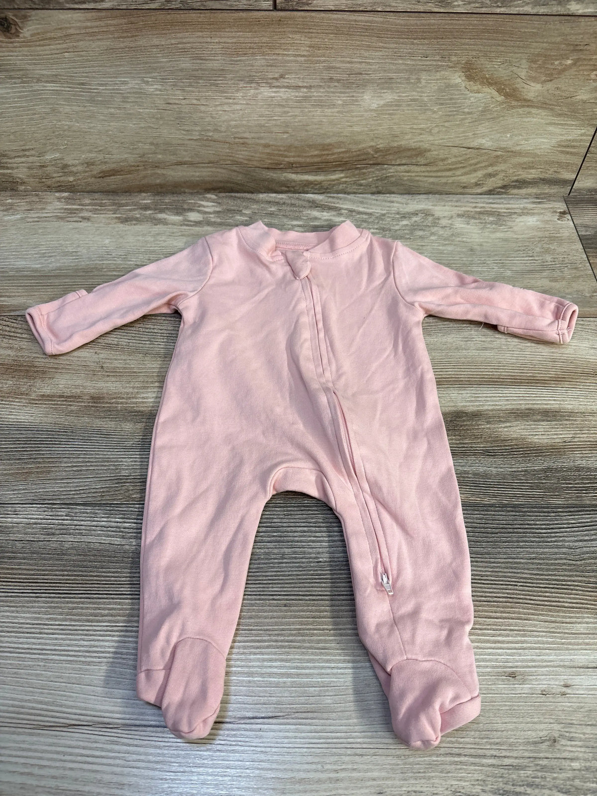 Front view of pink Aablexema organic newborn sleeper showcasing long sleeves, zip front, and covered feet on wood grain