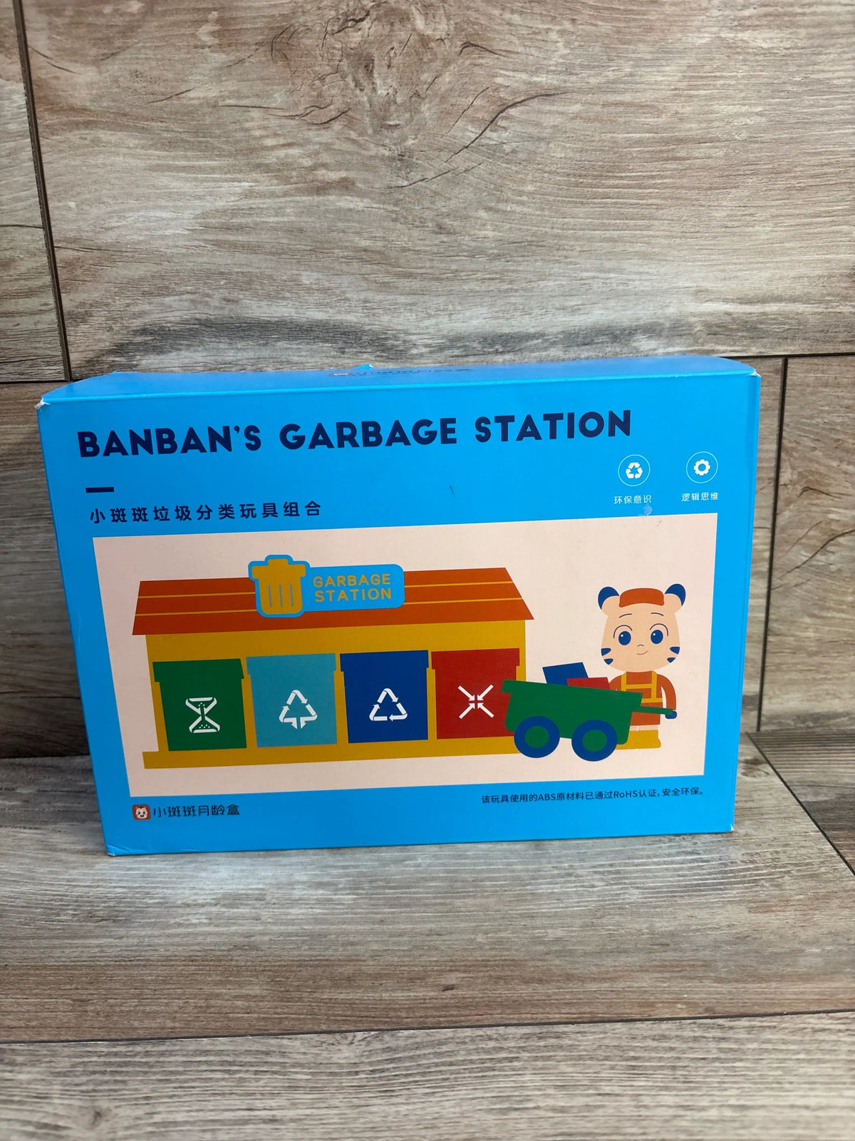 Front view of Banban’s Garbage Station Play Set box showcasing four sorting bins and recycling-themed artwork on a wood floor