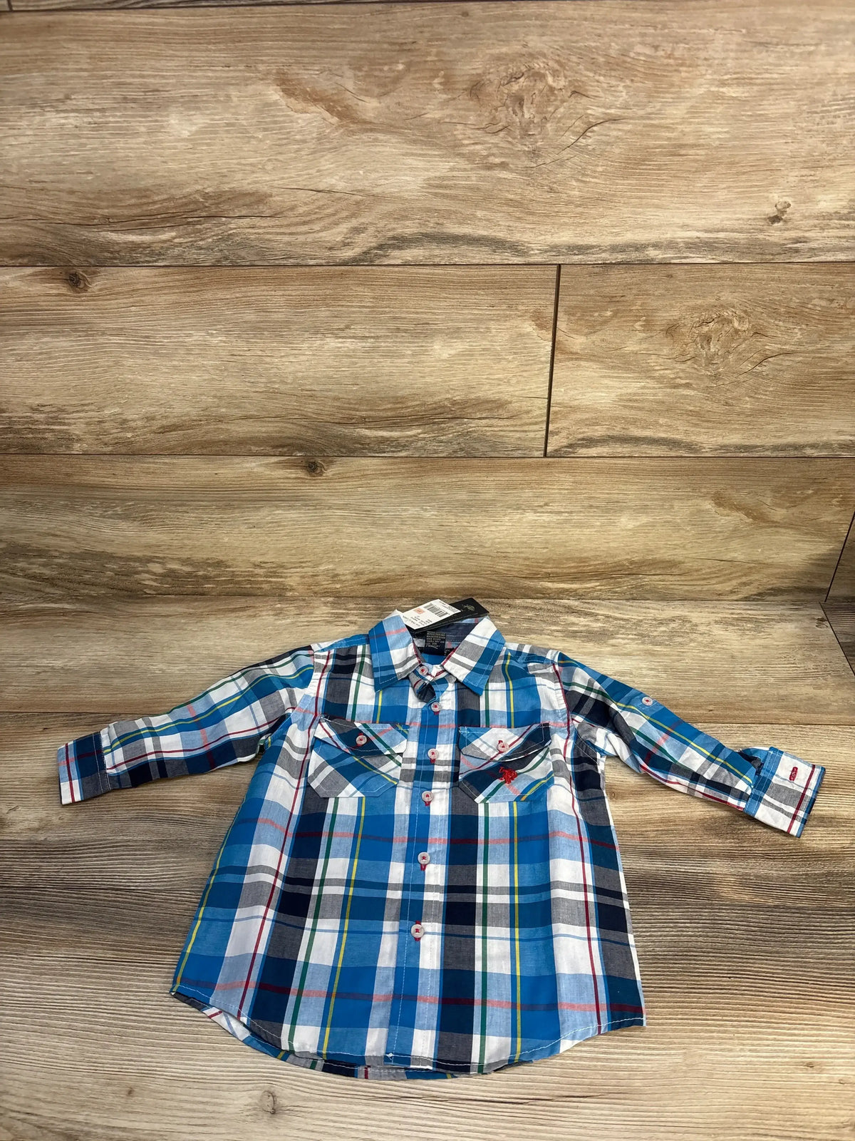 Blue and white plaid long sleeve button-up shirt for kids on wooden background