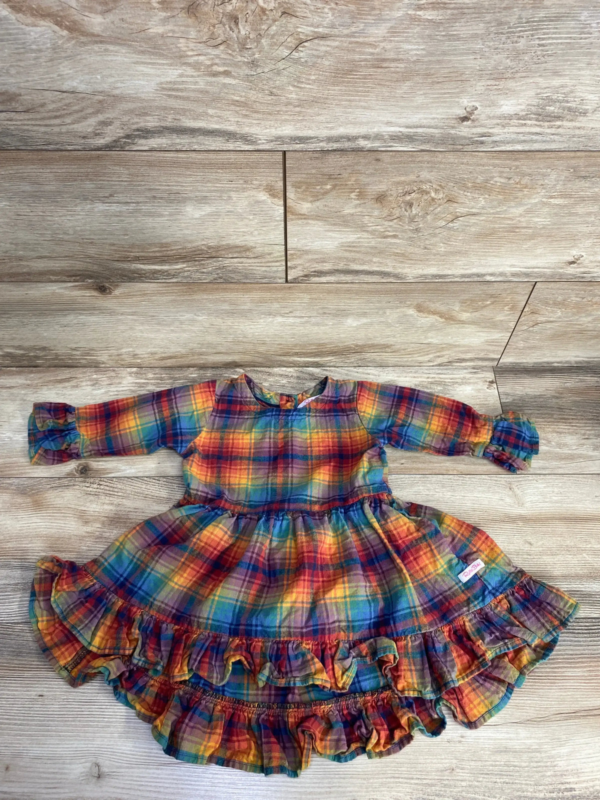 Colorful long-sleeve plaid baby dress with ruffled hem and matching diaper cover on wooden floor