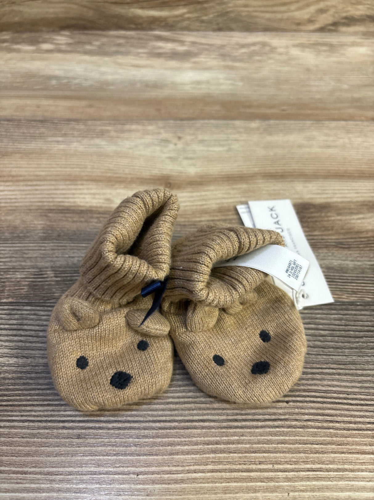 Front view of Janie & Jack baby bear sweater booties showcasing embroidered bear faces and ribbed ankle cuffs on a wood tabletop