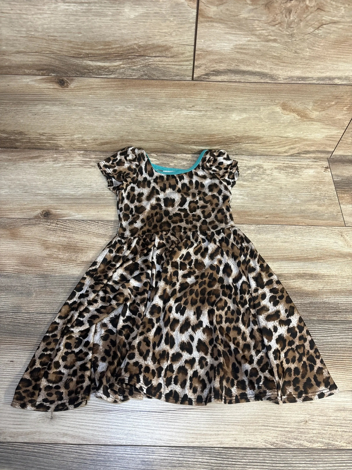 Leopard print short-sleeve toddler dress on wood floor, gently used children's clothing