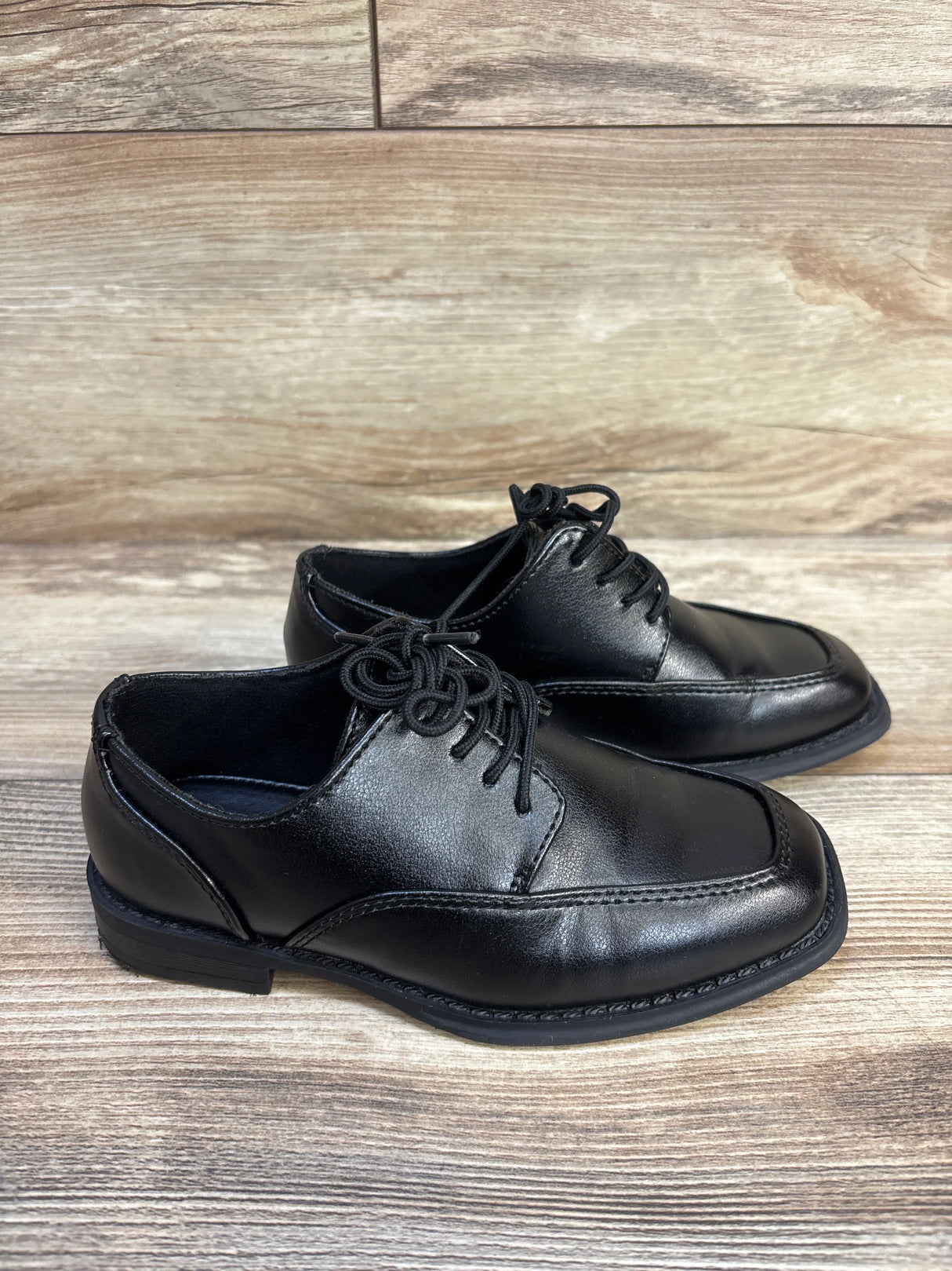 Black kids dress shoes with laces on wood surface, gently used, formal children’s footwear