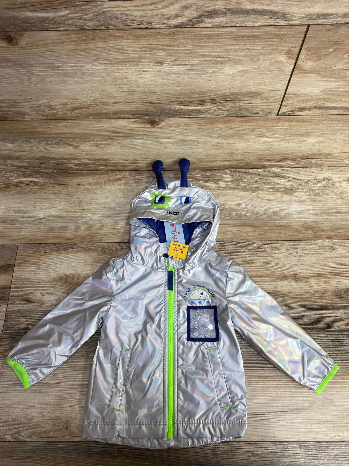 Silver kids' hooded rain jacket with green zipper and playful alien face on hood