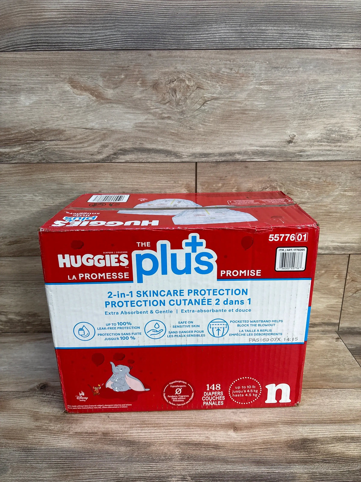 Front-facing Huggies Plus Little Snugglers newborn diaper box with 2-in-1 skincare protection label, 148 count, on wood floor