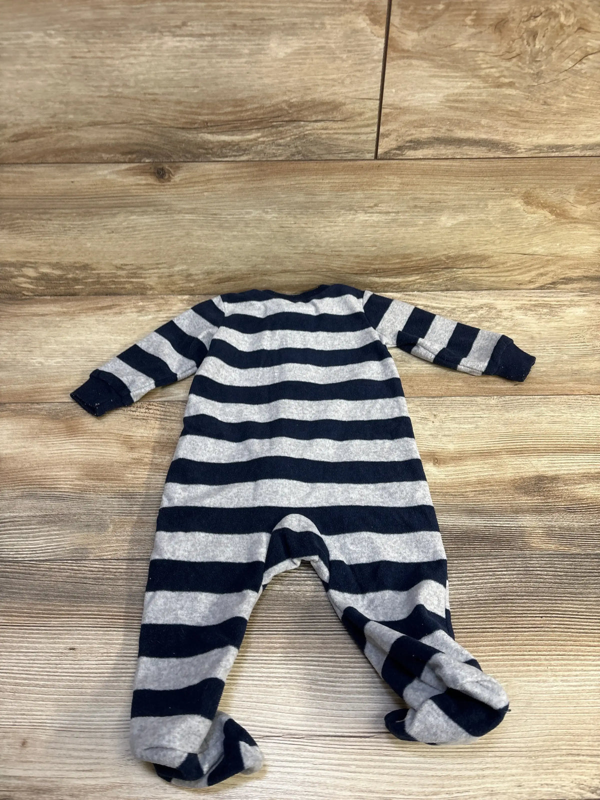 Flat-lay back view of grey and navy striped footed blanket sleeper showing sleeves and built-in feet on wood background