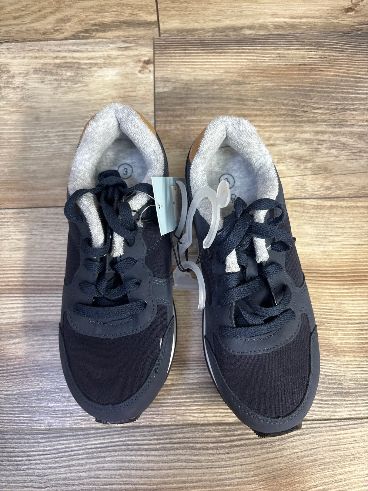 Top view of navy Cat & Jack toddler sneakers showing lace-up front, padded gray inner lining and faux-suede heel on wood floor
