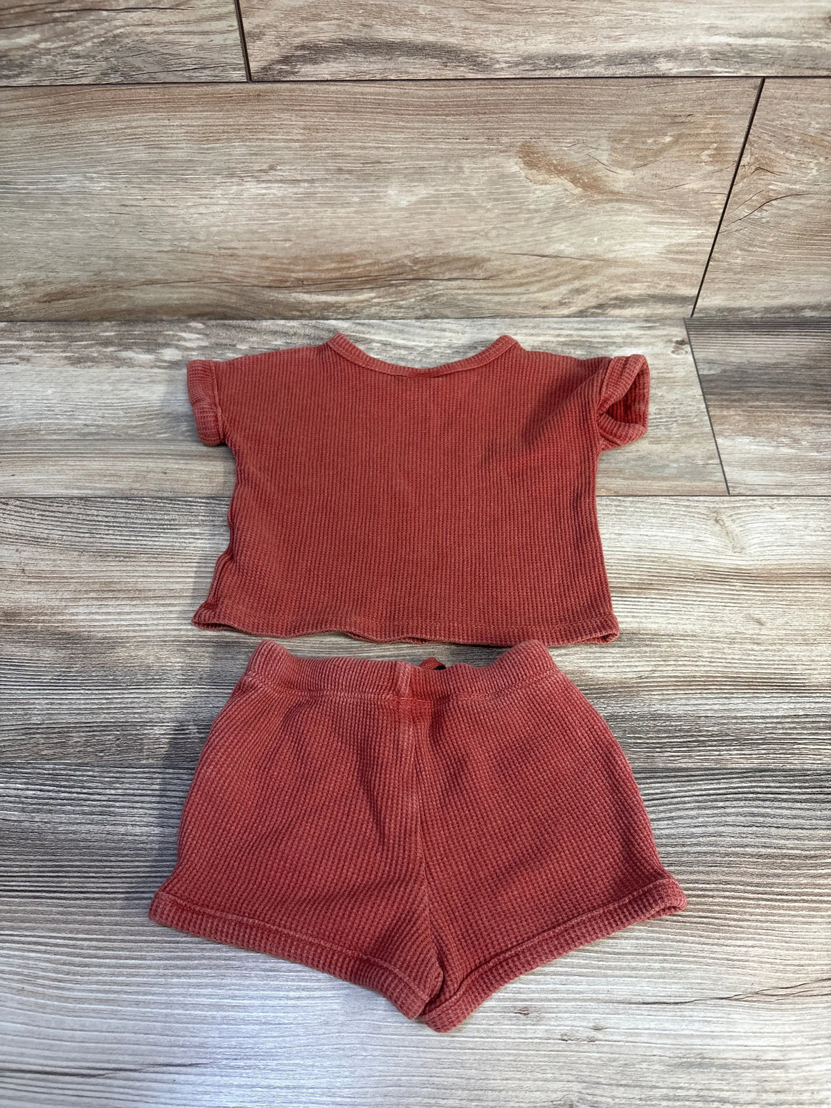 Top view of Cat & Jack two-piece rust waffle knit shirt and shorts set showcasing waffle knit fabric on wood-look flooring