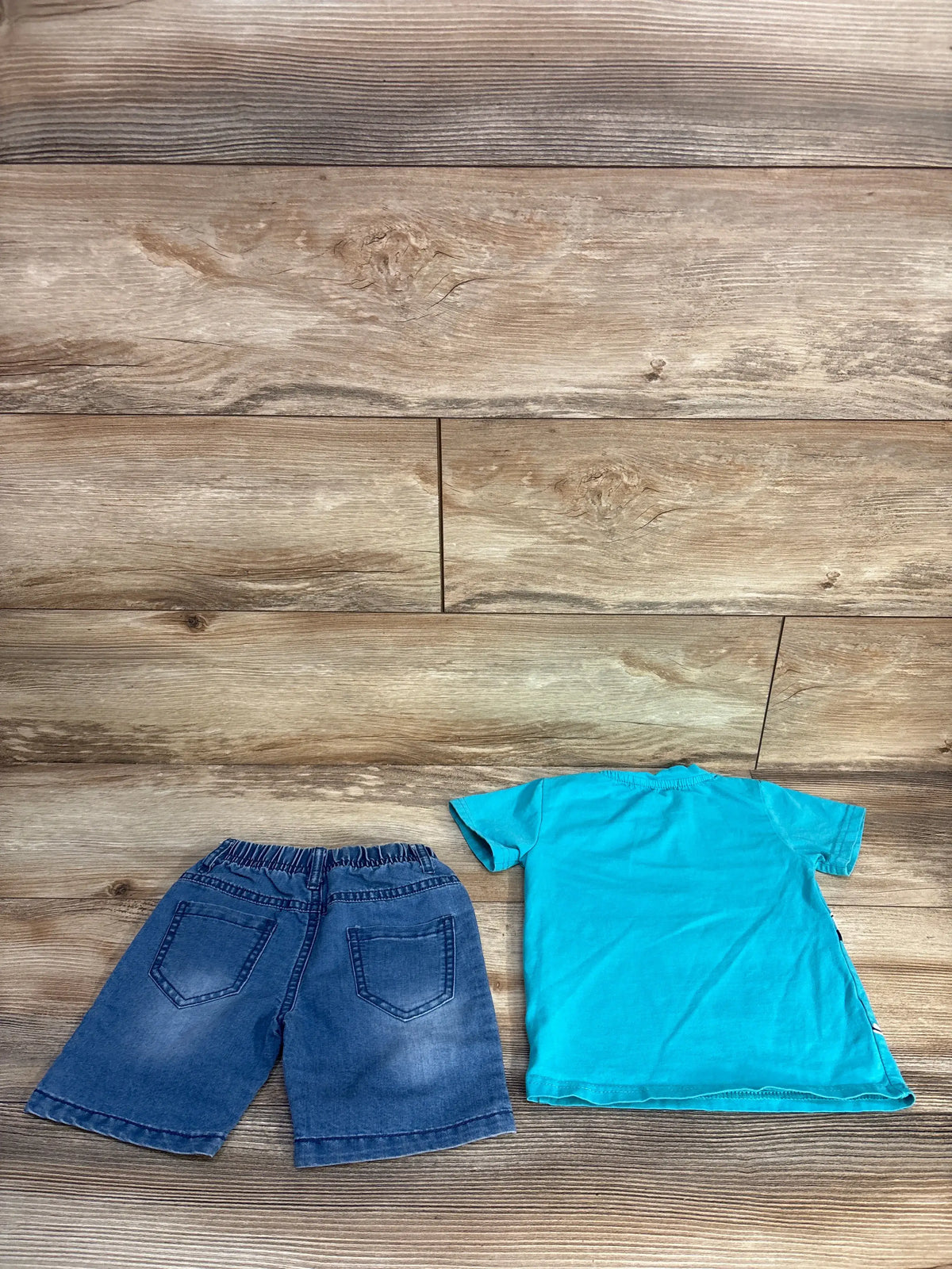 Overhead view of Pansee two-piece shirt and shorts set showcasing blue shirt and pocketed shorts on a wood background